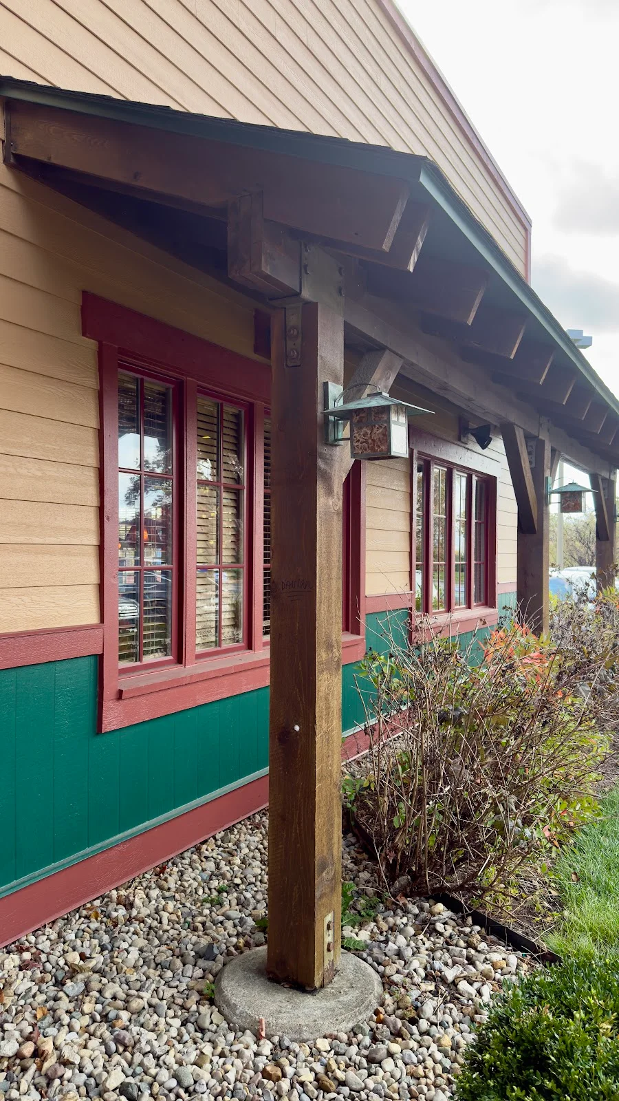 Covered patio walkway with structural timber columns and burgundy windows